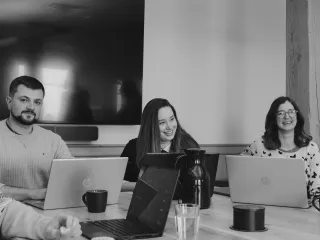 Group of people working on laptops, smiling.